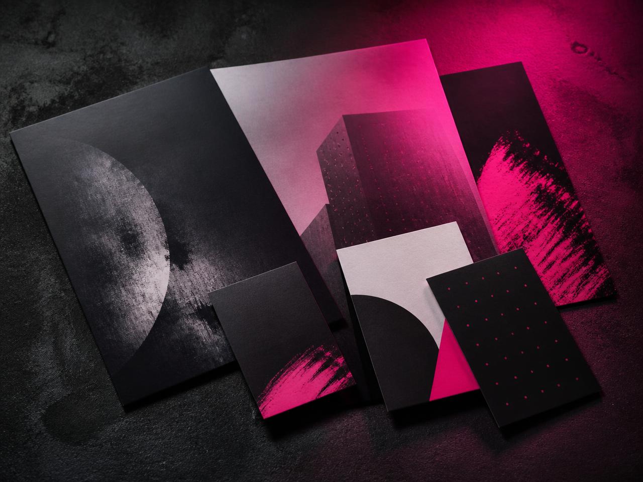 Printed brand collateral fanned on dark concrete under magenta light